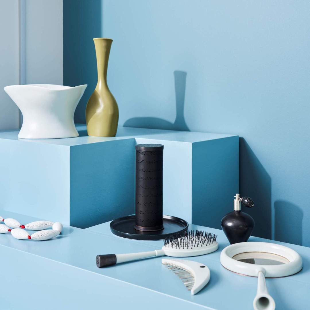Photo of pale-coloured ceramic vessels laying on blue-painted plinths in a display case